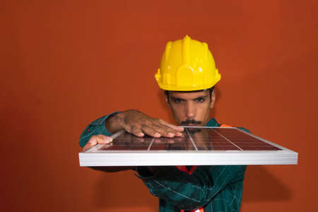 Solar worker in protective work looking on focus photovoltaic panel isolated. Concept of designing power plants.の写真素材