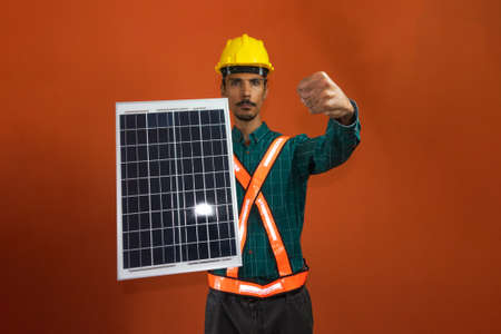 Solar worker in protective work clothes holding photovoltaic panel isolated. Concept of designing power plants.の写真素材
