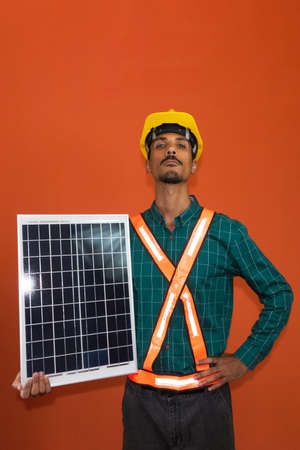 Solar worker in protective work clothes holding photovoltaic panel isolated. Concept of designing power plants.の写真素材