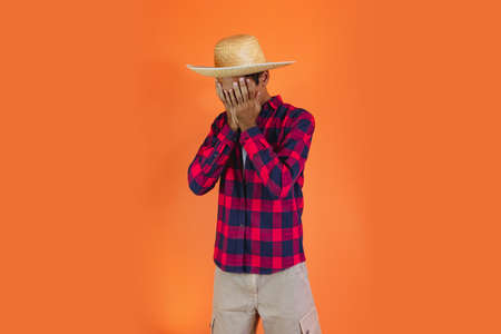 Black Man With Junina Party Outfit  Isolated on Orange Background.  Young man wearing traditional...
