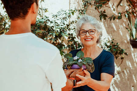 Happy interracial family. Son gives a gift to his mother in the house garden.