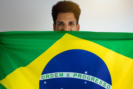 Brazilian Black Man Fan with Soccer Team Shirt Isolated on White. Sport Fan With Flag Celebrating...