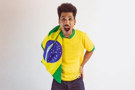Brazilian Black Man Fan with Soccer Team Shirt Isolated on White. Sport Fan With Flag Celebrating...