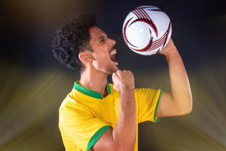 Brazilian Football Black Player Holding Ball and Celebrating, Isolated on Black Background.の写真素材