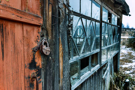 Rusty lock hanging on an old abandoned wooden houseの写真素材