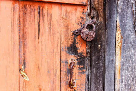 Rusty lock hanging on an old abandoned wooden houseの写真素材
