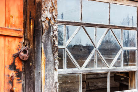 Rusty lock hanging on an old abandoned wooden houseの写真素材
