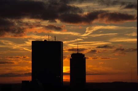 sillhouetted buildings against golden clouds at sunset.