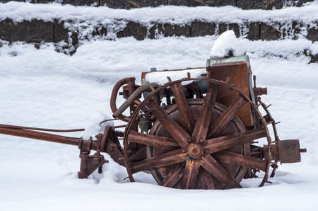 An old piece of rusted farm equipment sits in snow.の写真素材
