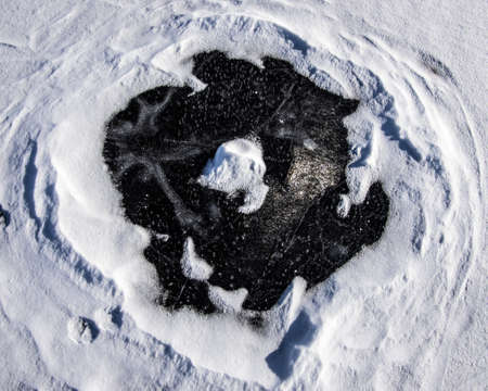 Snow covered ice on a pond, cleared in a circle to reveal the ice underneathの写真素材