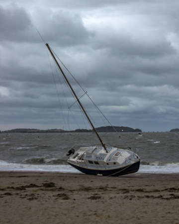 A sailboat washed ashore on the beach in Quincy Ma after a strong storm.の写真素材