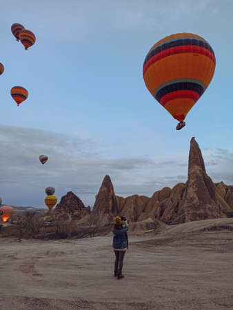 Woman watching colorful hot air balloons over the fairy chimneys in Cappadociaのeditorial素材