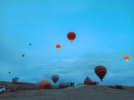 Colorful hot air balloons flying at the sunrise with rocky landscape in Cappadocia, Turkeyのeditorial素材