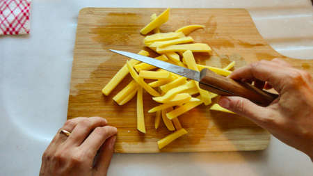 Raw Potato sliced strips prepared for French fries with wooden backgroundの写真素材