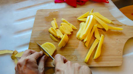 Raw Potato sliced strips prepared for French fries with wooden background