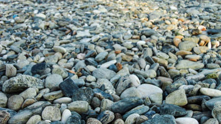 Stony beach on a sunny day. Background of different pebbles from above on the beach