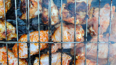 Chicken wings on barbecue grill with fire close up. Chicken meat on the grill