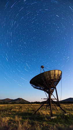 Photorealistic antique astrolabe suspended against dark starry sky with visible star trails, subtle metallic reflections, no text, no human presence, spacious copy spaceの素材