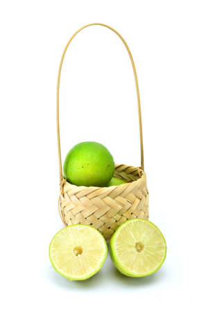 Green lemon in the basket isolated on white backgroundの写真素材