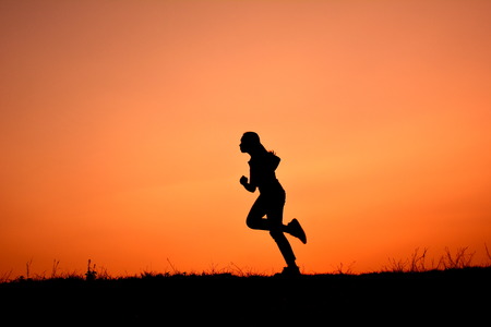 Silhouette women run at sky sunsetの写真素材