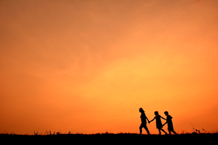 Silhouette of kids playing together at sunsetの写真素材
