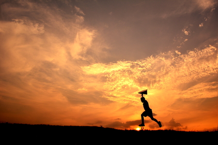 Silhouette boy holding rocket in the sunset. Concept big dreamの写真素材