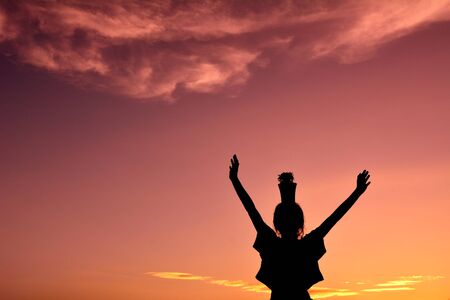 Silhouette girl hands holding plant at sunset