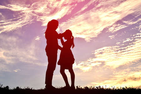 silhouettes mother and daughter playing at sunset