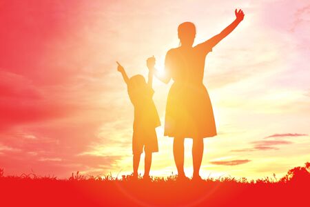 silhouettes mother and little daughter playing at sunsetの写真素材