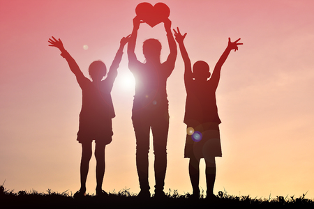 Silhouette mother and children holding heart shape at sunset. Concept mother dayの写真素材