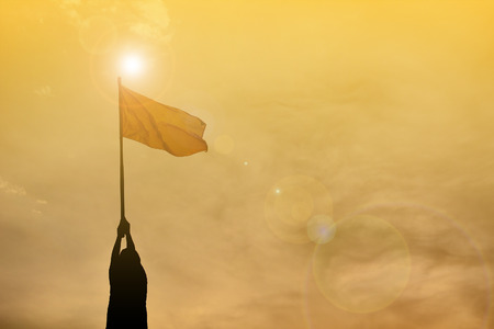Silhouette boy holding flag at sunset. Concept successの写真素材