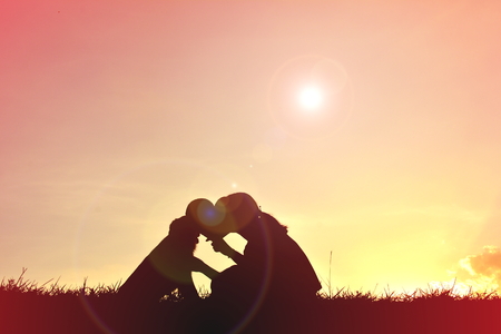 Silhouette women playing with dog at sunsetの写真素材