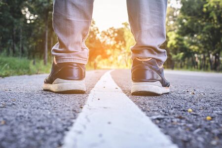 Feet of man on road and nature background ,alone and wait to travel, selective and soft focusの写真素材