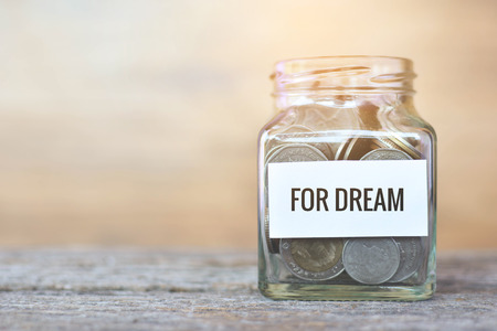 Money in a glass jar with "dream" word. concept siphons moneyの写真素材