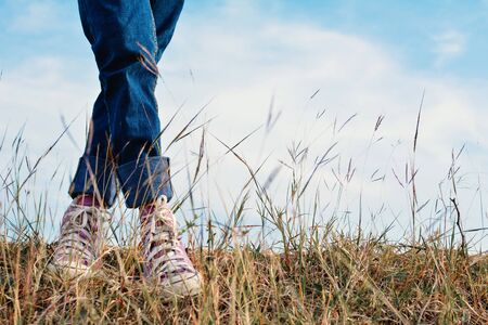Happy Asian girl standing in grass and blue sky background, Relax time on holiday concept travel ,color of vintage tone and soft focusの写真素材