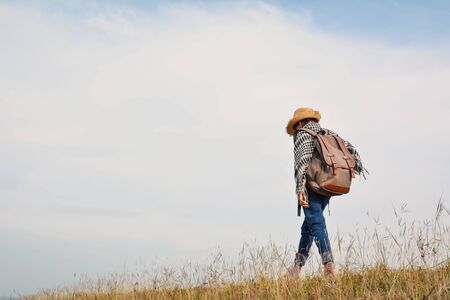 Happy Asian girl  standing in grass and blue sky background, Relax time on holiday concept travel ,color of vintage tone and soft focusの写真素材