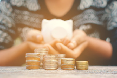 Hand holding piggy bank and coin on old wood tree bokeh background.color of hipster tone concept save moneyの写真素材