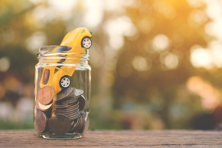 coin with car on old wood and tree bokeh background with sunlight, a color of vintage tone concept save money selective and soft focusの写真素材