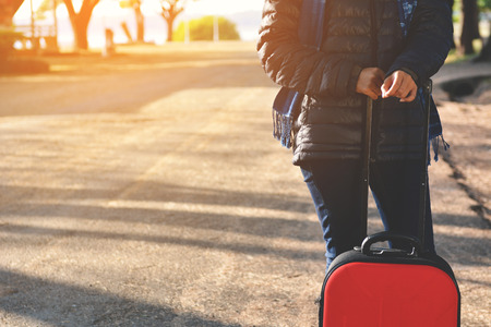 Happy women with red luggage walking on park concept travelの写真素材