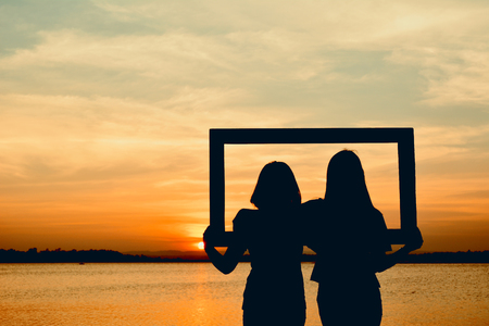 Silhouette of women holding frame at the sky sunset concept valentine dayの写真素材