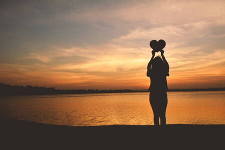Silhouette of women hands holding heart shape at the sky sunset background. concept love valentine dayの写真素材
