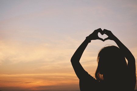 Silhouette hand of women in the heart shape at the sky sunset background. concept love valentine dayの写真素材