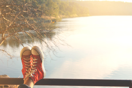 Feet red sneaker a girl in nature and relax time on holiday. selective and soft focus color of vintage toneの写真素材
