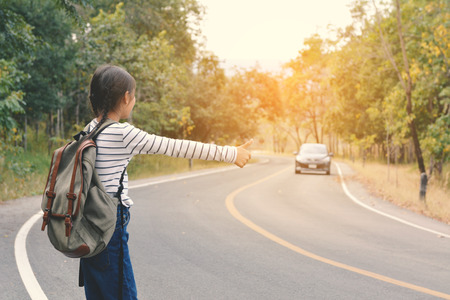 Happy Asian girl backpack in the road and forest background, Relax time on holiday concept travel ,color of vintage tone and soft focusの写真素材