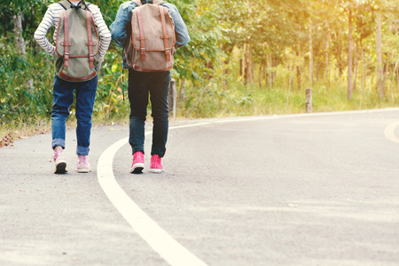 Happy Asian children backpack in the road and forest background, Relax time on holiday concept hitchhiking trip,color of vintage tone and soft focusの写真素材