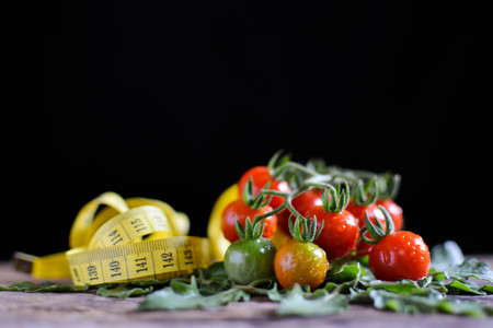 Still life group of tomato with measuring tape on old wood and black background, soft focusの写真素材