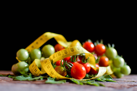 Still life group of tomato with measuring tape on old wood and black background, soft focusの写真素材