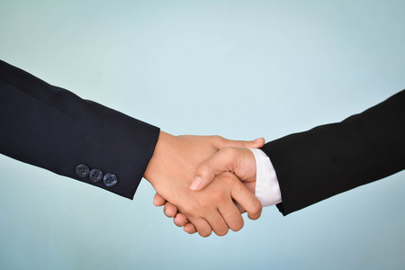 Businesswomen shake hand in office, selective of focus and blue backgroundの写真素材