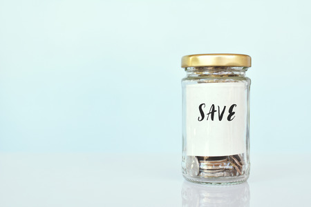 Close up coin in glass jar on blue background,concept save money color of vintage tone selective and soft focusの写真素材