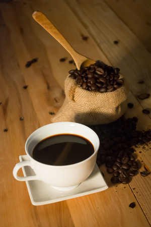 Hot coffee cup and bean in bag on wood background vintage tone,selective and soft focusの写真素材